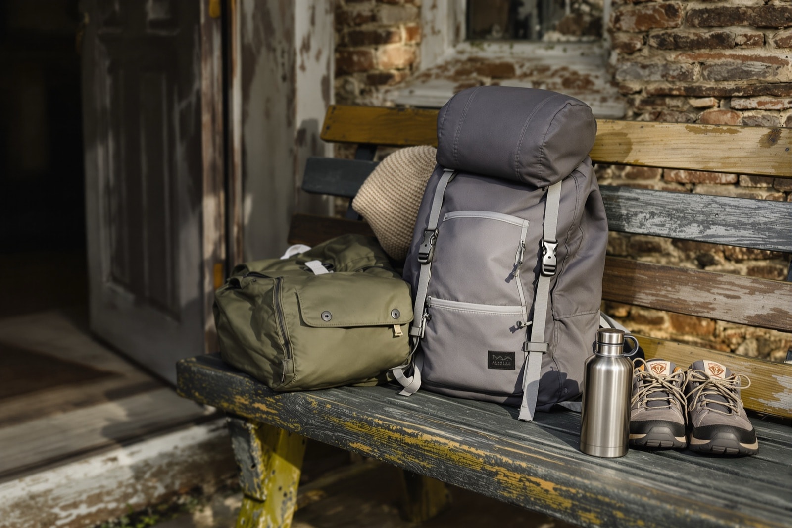 Waterproof jacket, walking shoes and a small rucksack laid out on a wooden bench by a door